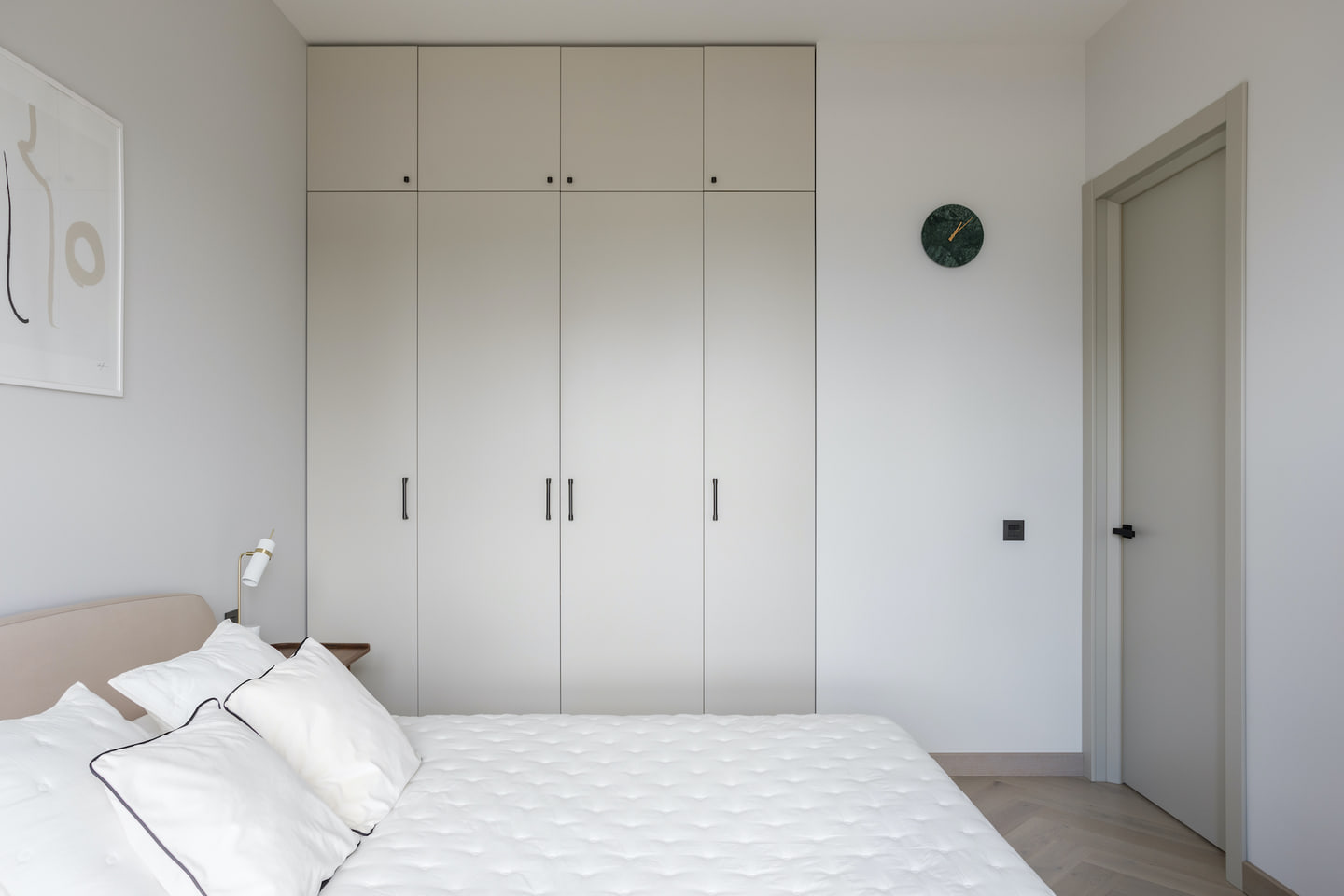 Bedroom with a pale bed and full-height neutral wardrobes
