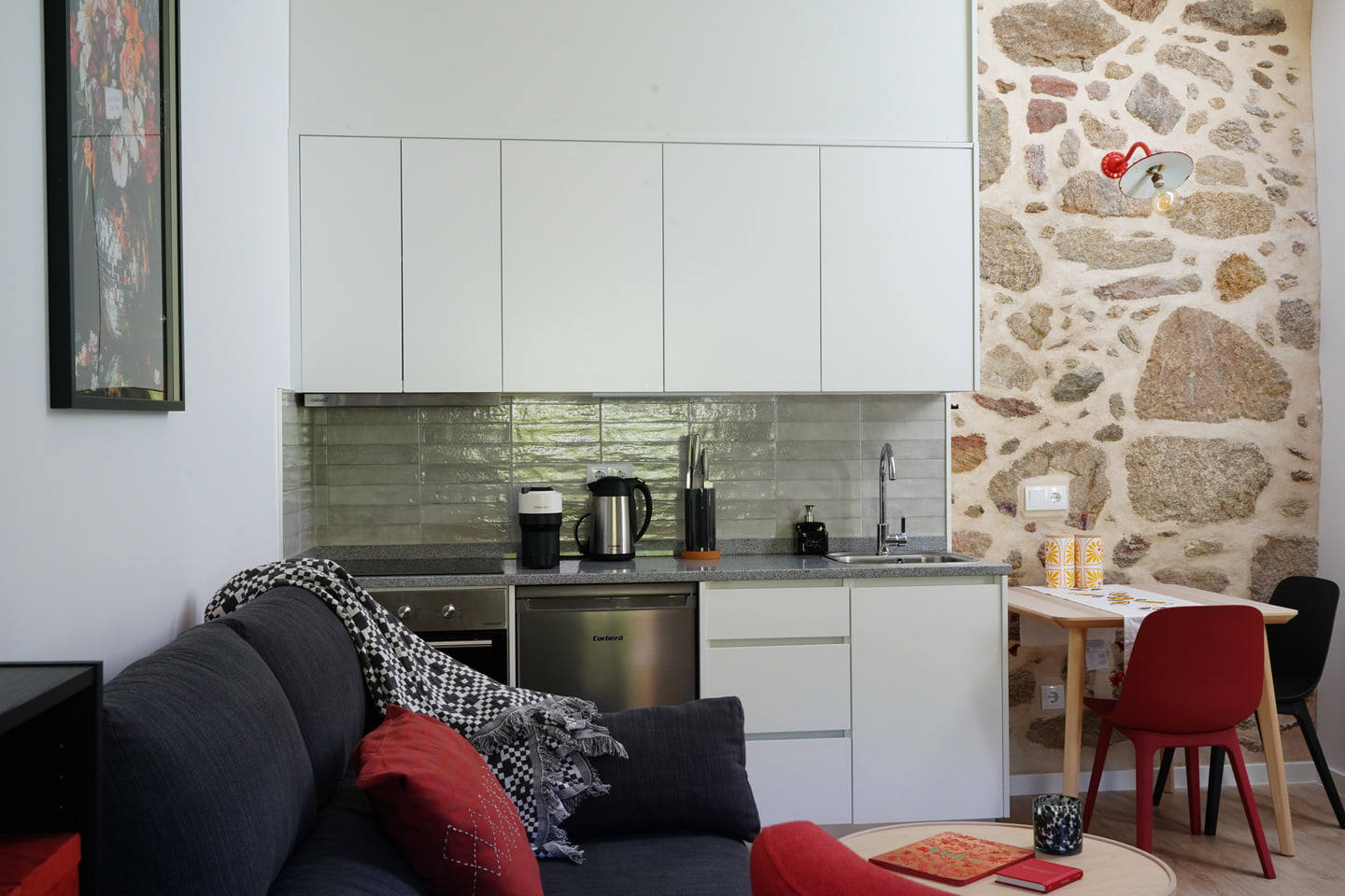 White kitchen beside an original stone wall in the Cerdal house