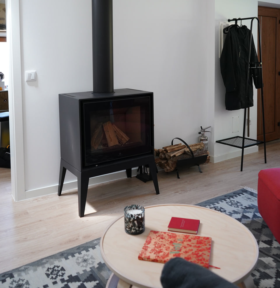 Living room with black stove, red chair and timber roof