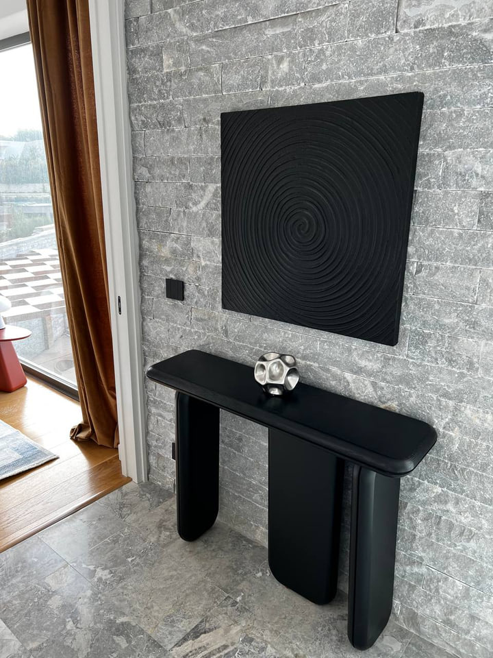 Black console and artwork against a stone wall