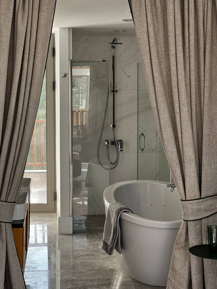 Stone-lined bathroom with freestanding bath and glass shower