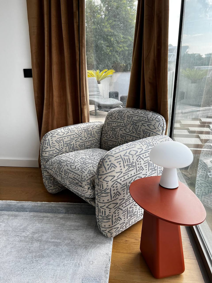 Patterned armchair and red side table by a window