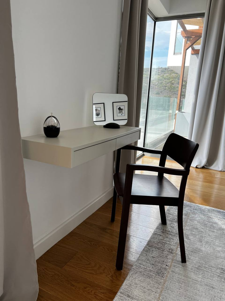 Pale wall console and black timber chair beside a terrace window